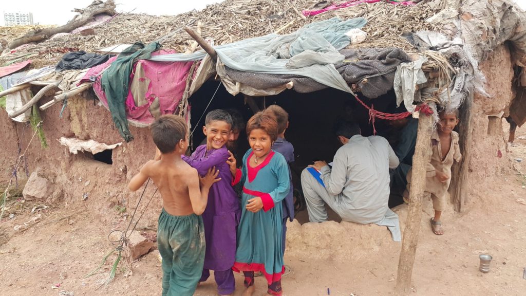 Figure 2: Researcher Saqib Hussain and Inayat Ullah conduct an interview with parents inside an impoverished shelter of a refugee family in Islamabad